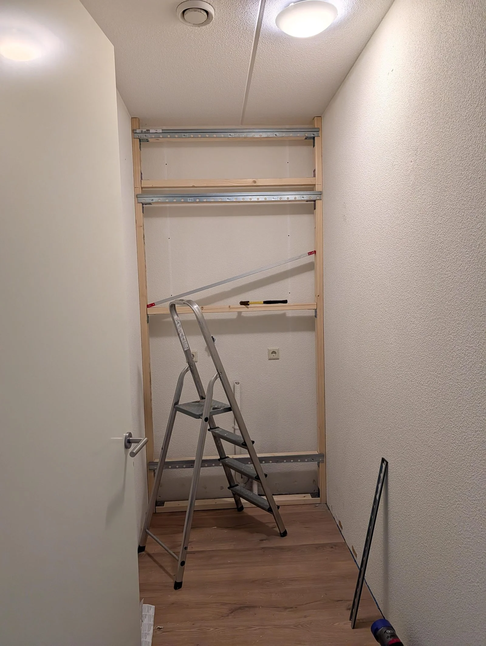 Telaio in legno completo con binari metallici di sospensione dentro la nicchia, scala a libro davanti