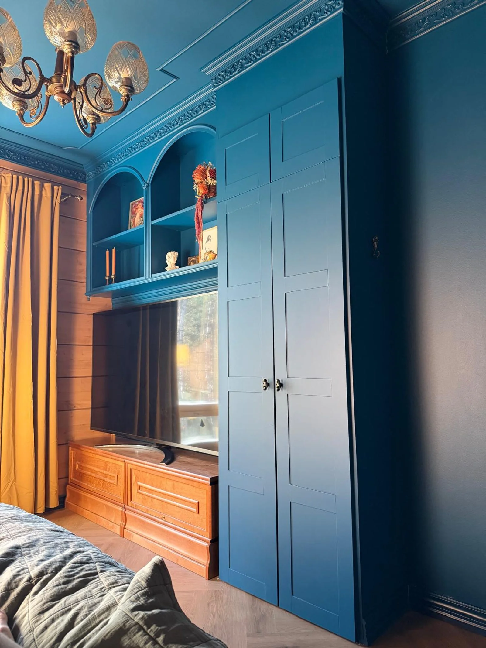 Parete attrezzata blu con armadio a tutta altezza, vani ad arco sopra la TV e soffitto blu