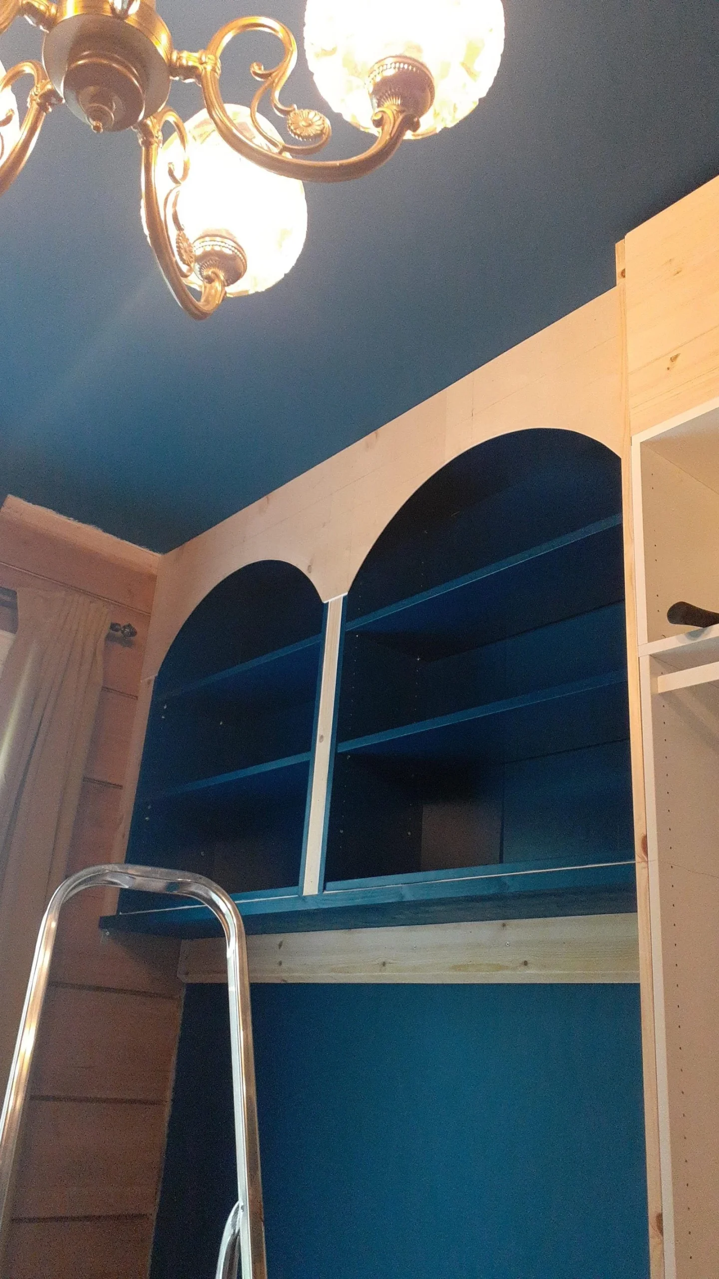 Arco in compensato grezzo appena montato davanti ai vani blu, pannello di chiusura al soffitto