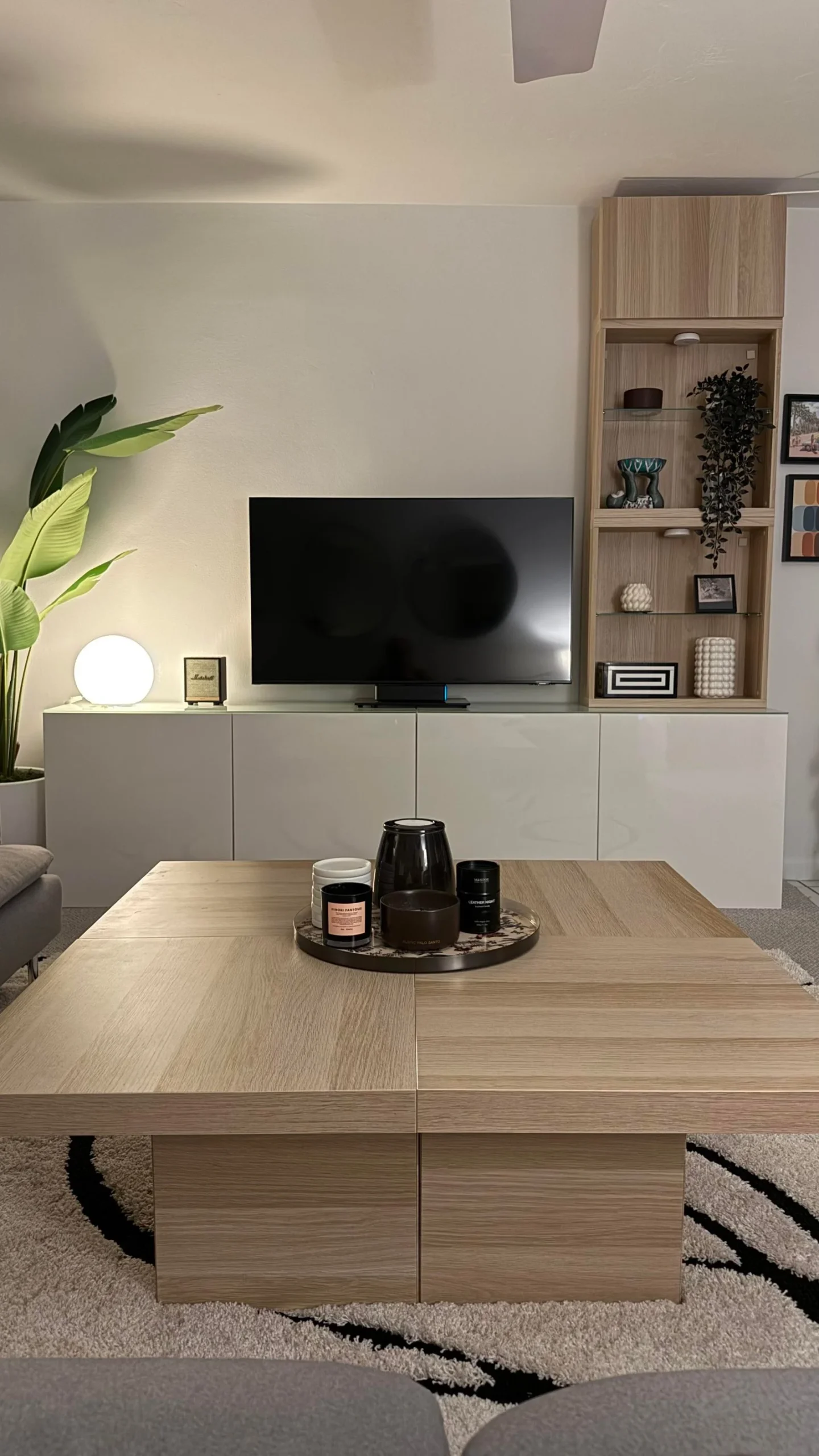 Soggiorno con mobile TV bianco lucido, colonna in rovere chiaro e grande tavolino quadrato in legno