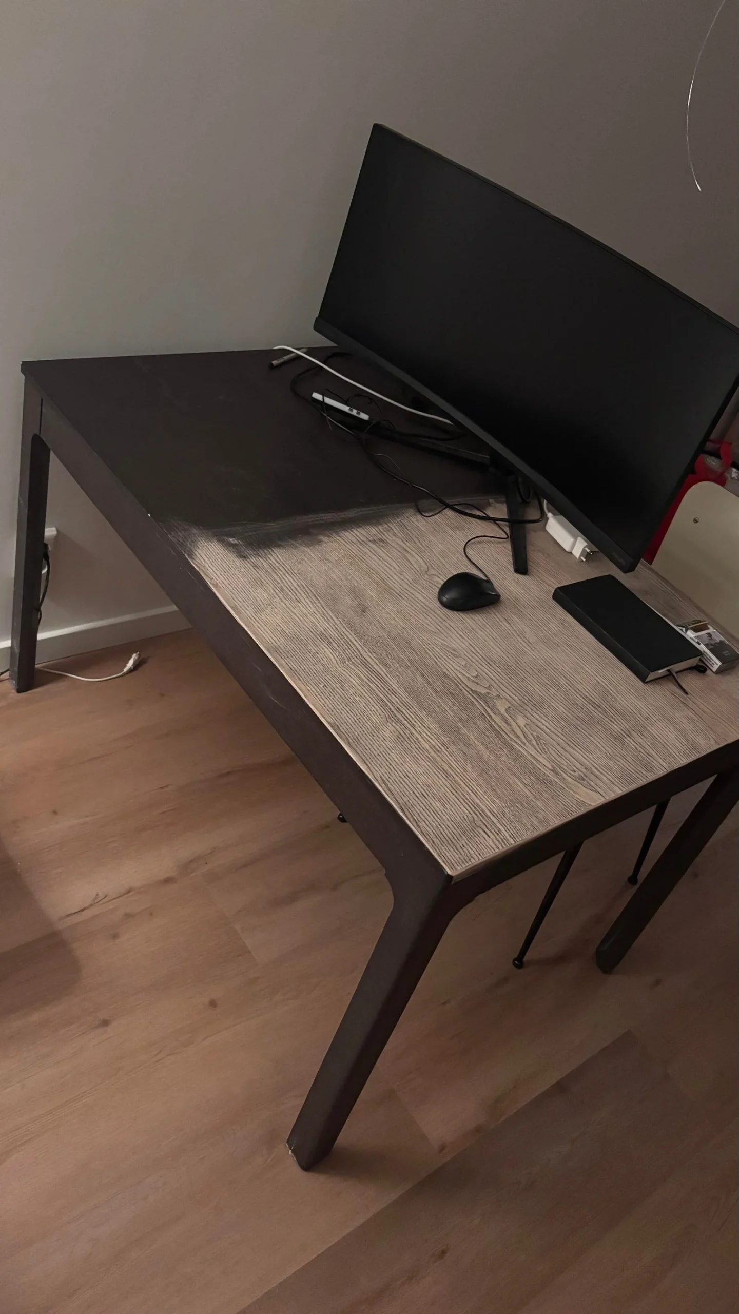 Piano di tavolo IKEA nero lucido con graffi e una zona già carteggiata che mostra il legno chiaro