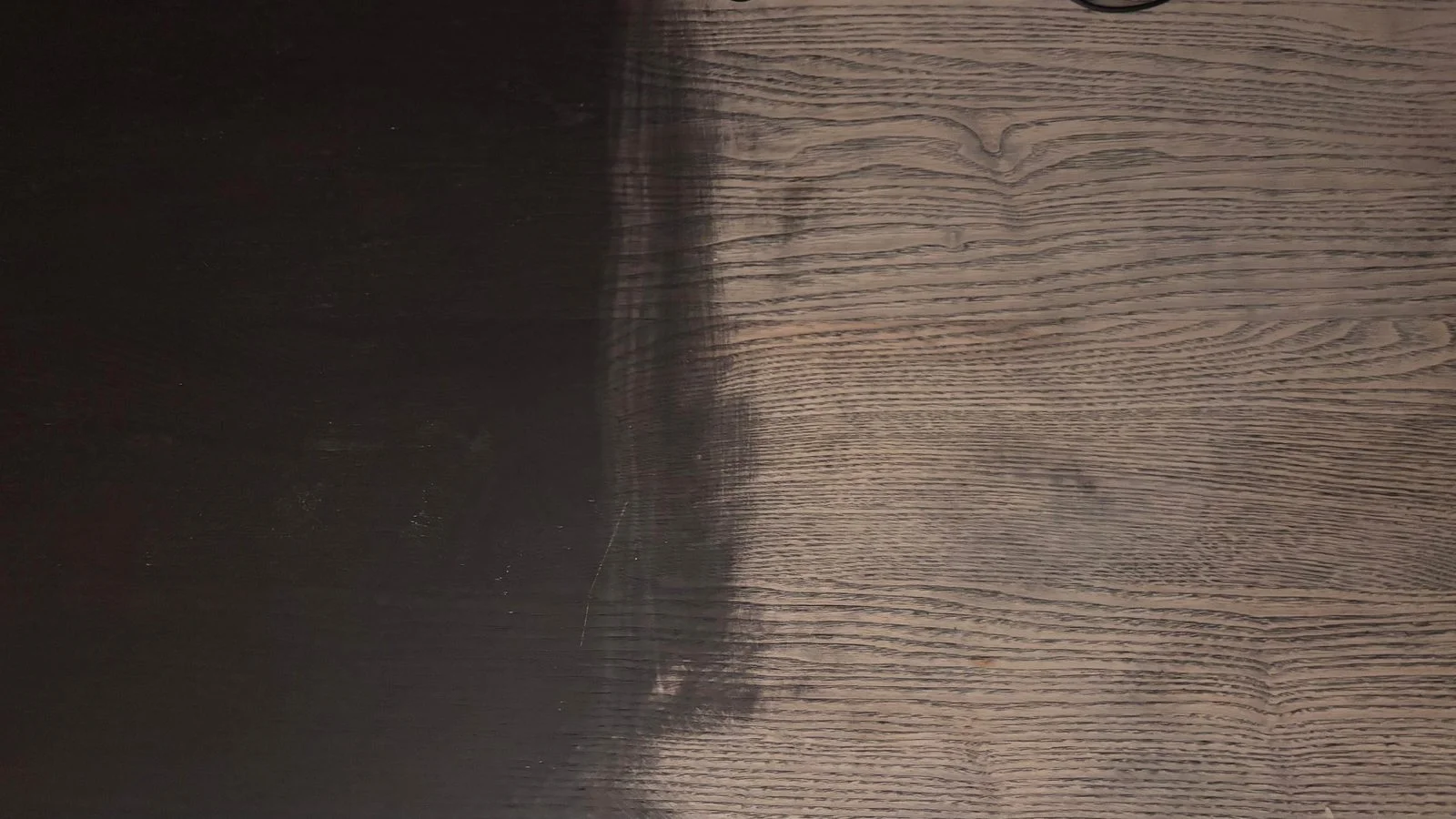 Dettaglio ravvicinato del passaggio fra finitura scura originale e legno carteggiato con venatura aperta
