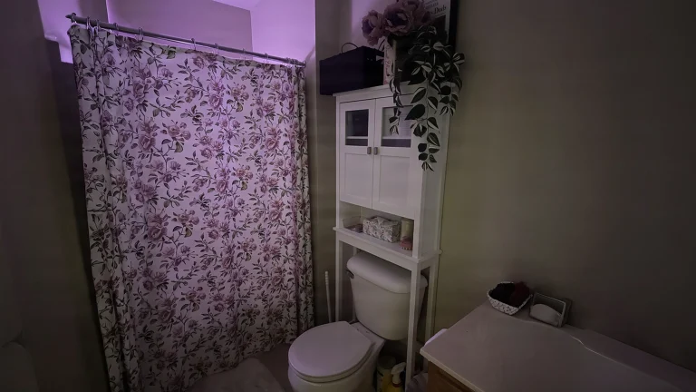 Arredare il bagno come un salotto: fiori, luce lilla e tessili coordinati per un piccolo rifugio da sitcom