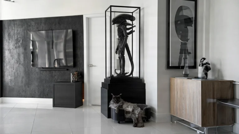 Parete TV nera e collezione horror: un soggiorno bianco e nero dove una sola vetrina fa da protagonista