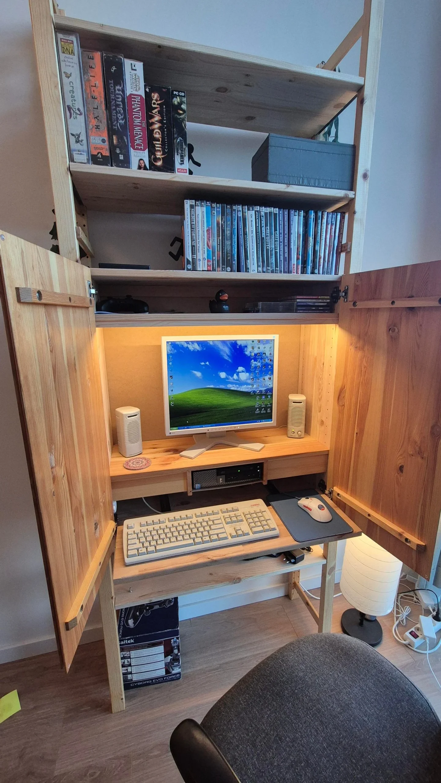 Libreria IVAR aperta con monitor, casse, PC orizzontale e cassetto tastiera estratto, luce LED sotto il ripiano