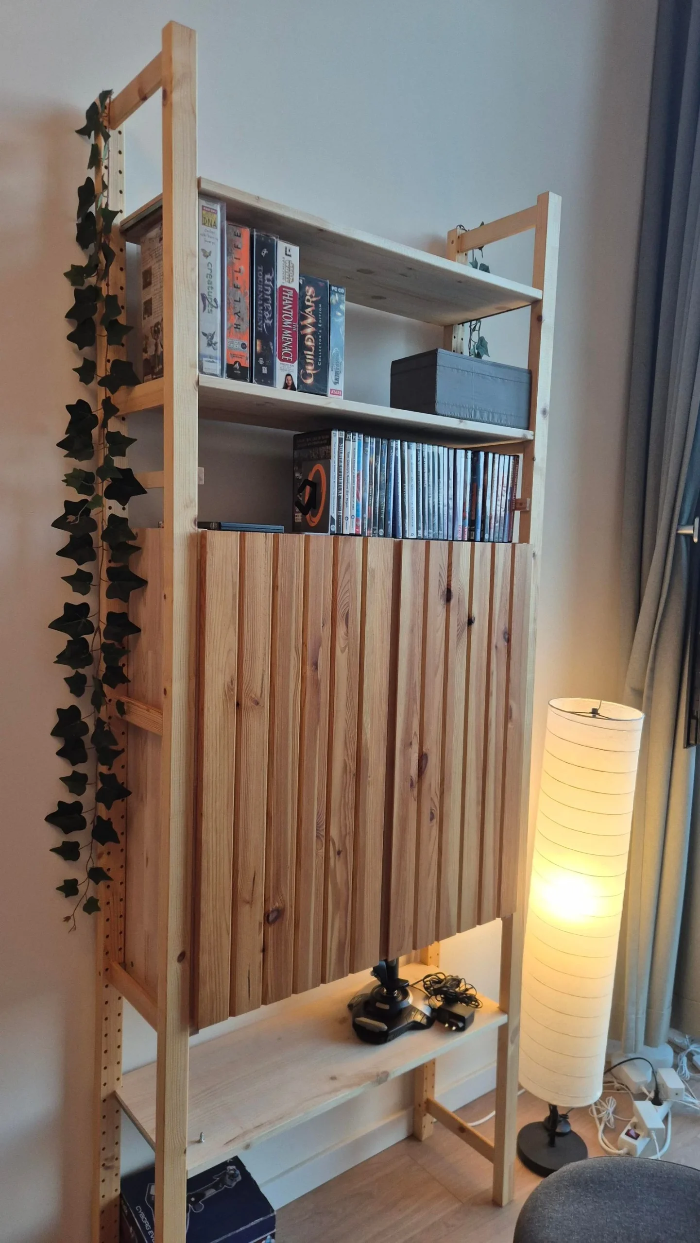 La stessa libreria IVAR con le ante chiuse a doghe verticali, piante e lampada da terra accanto