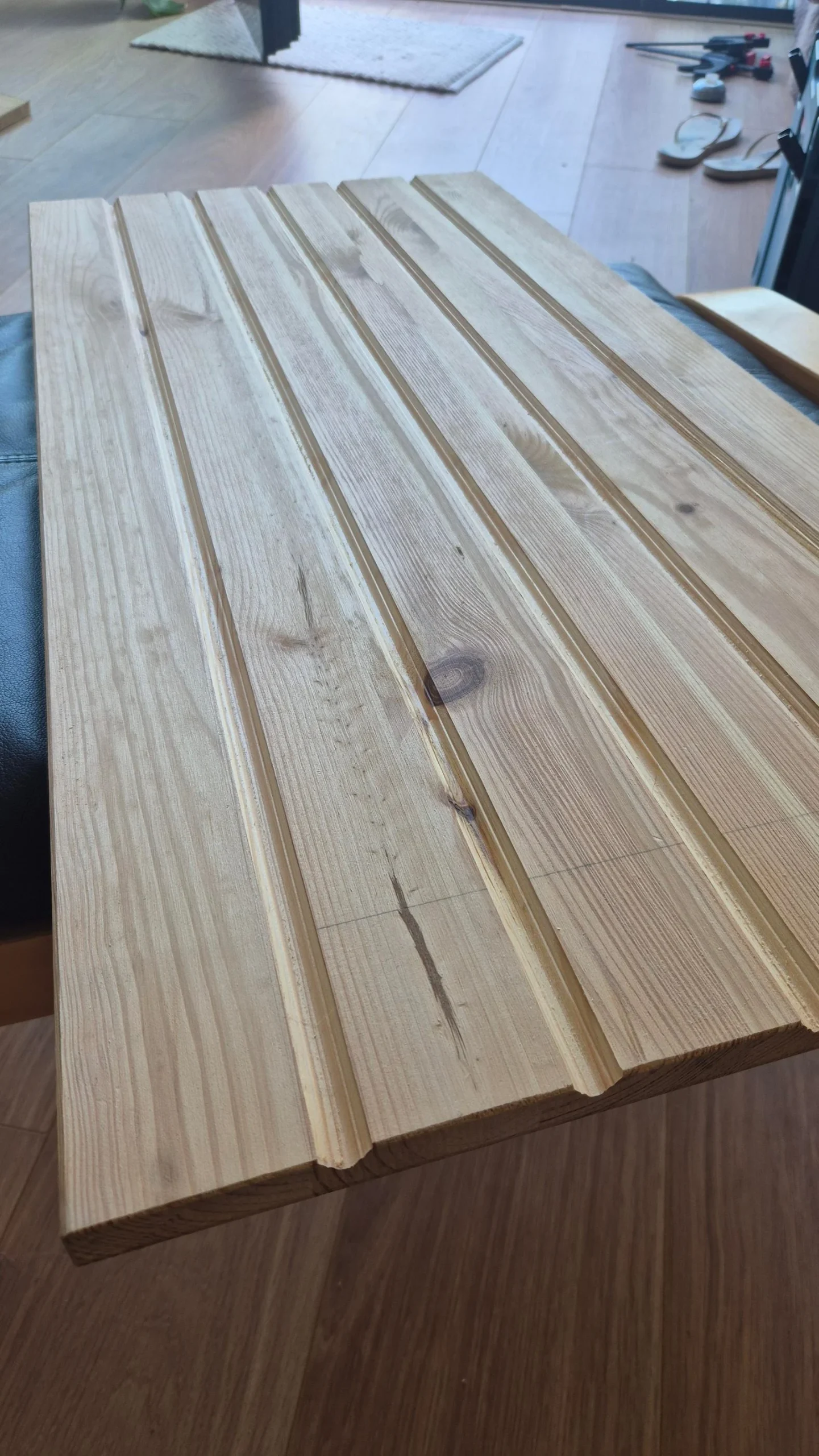 Tavola di pino chiaro con scanalature verticali parallele appoggiata su un tavolo