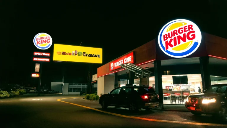 Pubblicità comparativa outdoor: il cartellone giallo che trasforma un marchio in un panino davanti al fast food